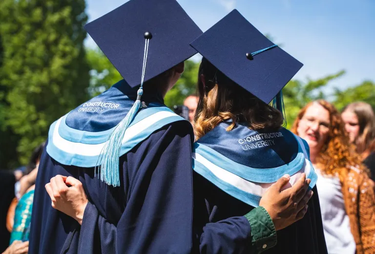Two Graduated Students Hug – Picture from the Back