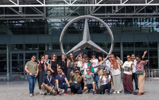 Group of people posing in front of the Mercedes-Benz logo