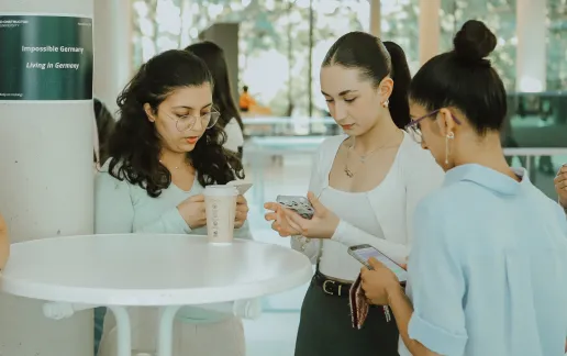Three students gather around a standing table during a campus event