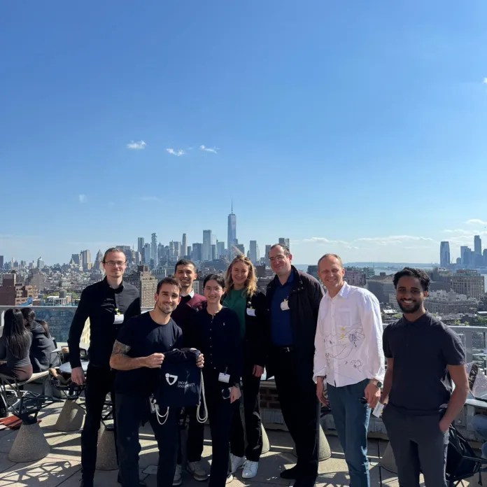 Alumni pose on a rooftop overlooking the Manhattan skyline in New York City