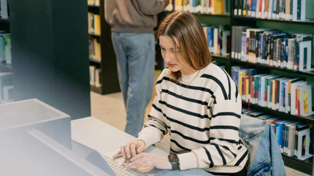 Student working on a laptop in the IRC