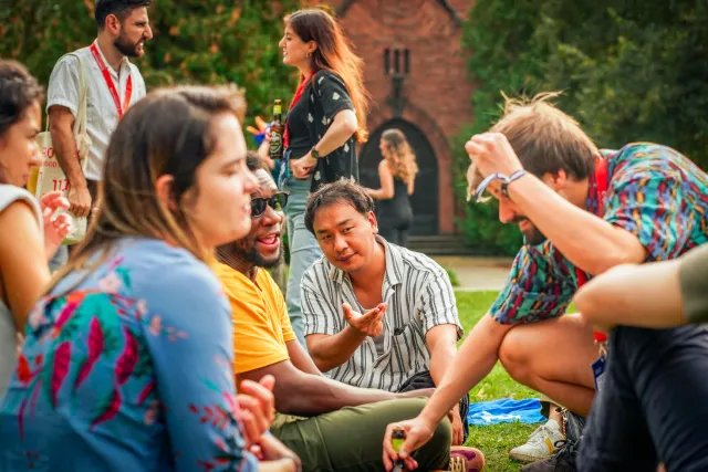 Alumni sitting together on the grass and socializing during an outdoor gathering