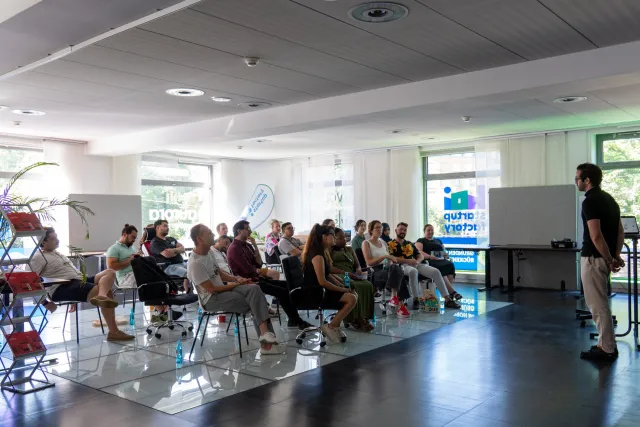 A speaker addresses a seated audience during a workshop